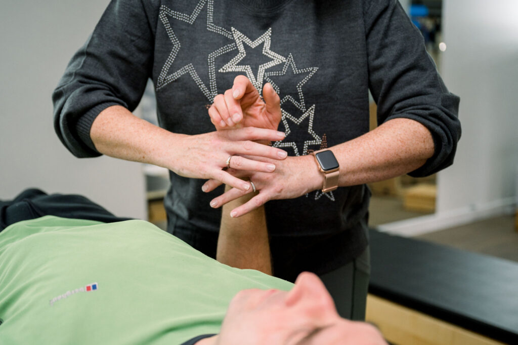 Image showing an example of a neural reset therapy session. A client is laid on their back with the practitioner holding their forearm.