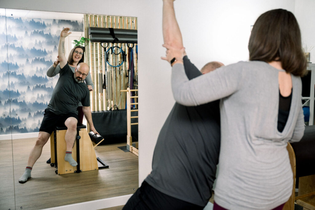 The Wunda Chair being used by a client under with support by an instructor during a private pilates session